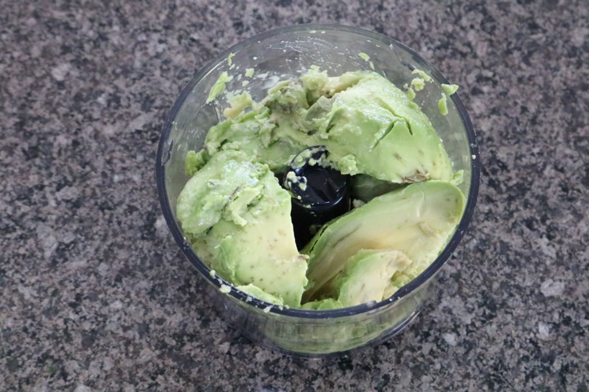 Avocados in a food processor ready for blending.