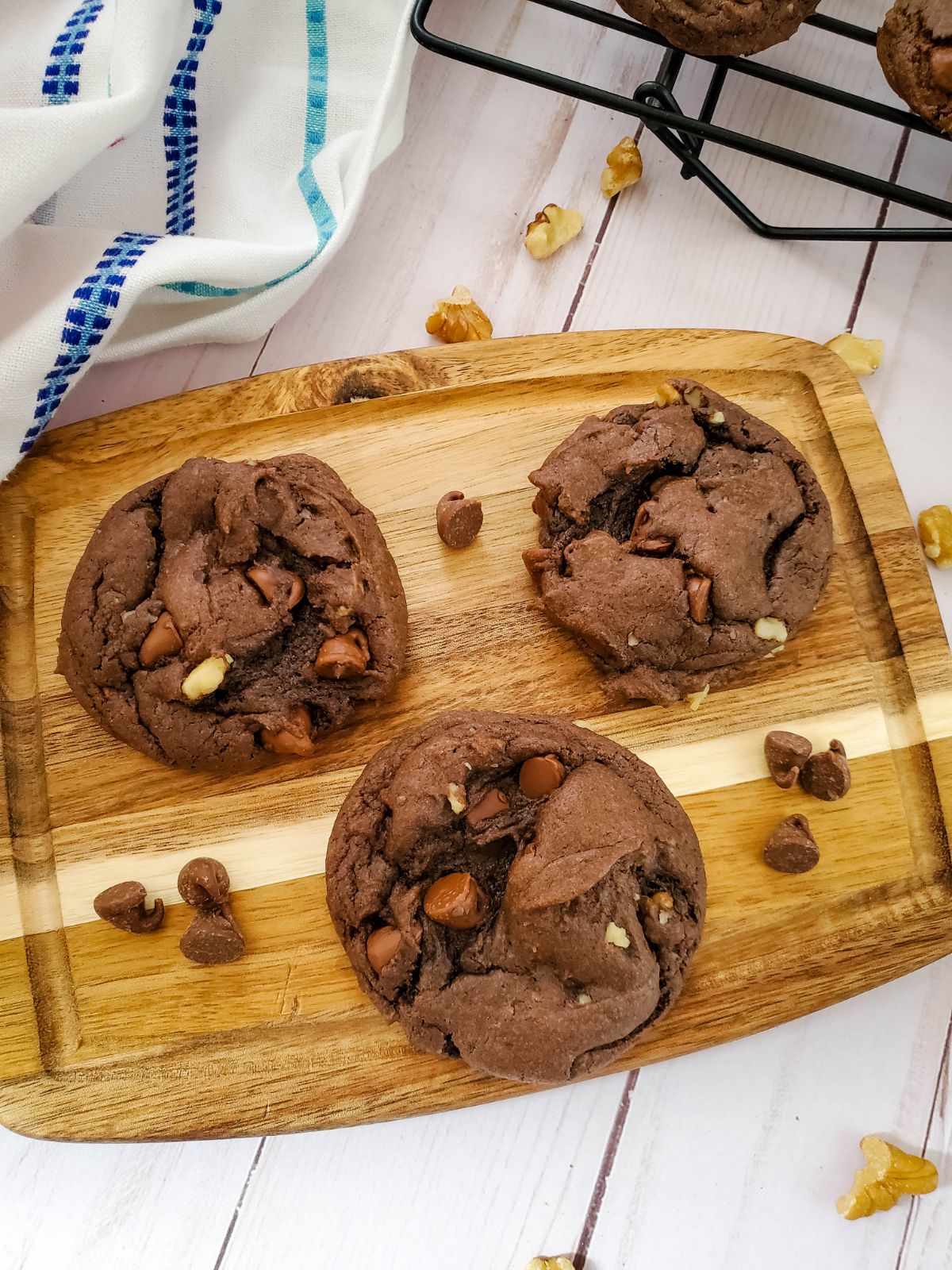 3 Double Chocolate Walnut Cookies on a wooden chopping board.