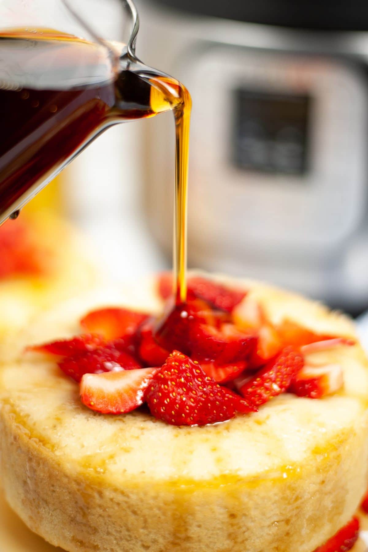 syrup being poured on a Giant Instant Pot Pancake topped with sliced Strawberries 