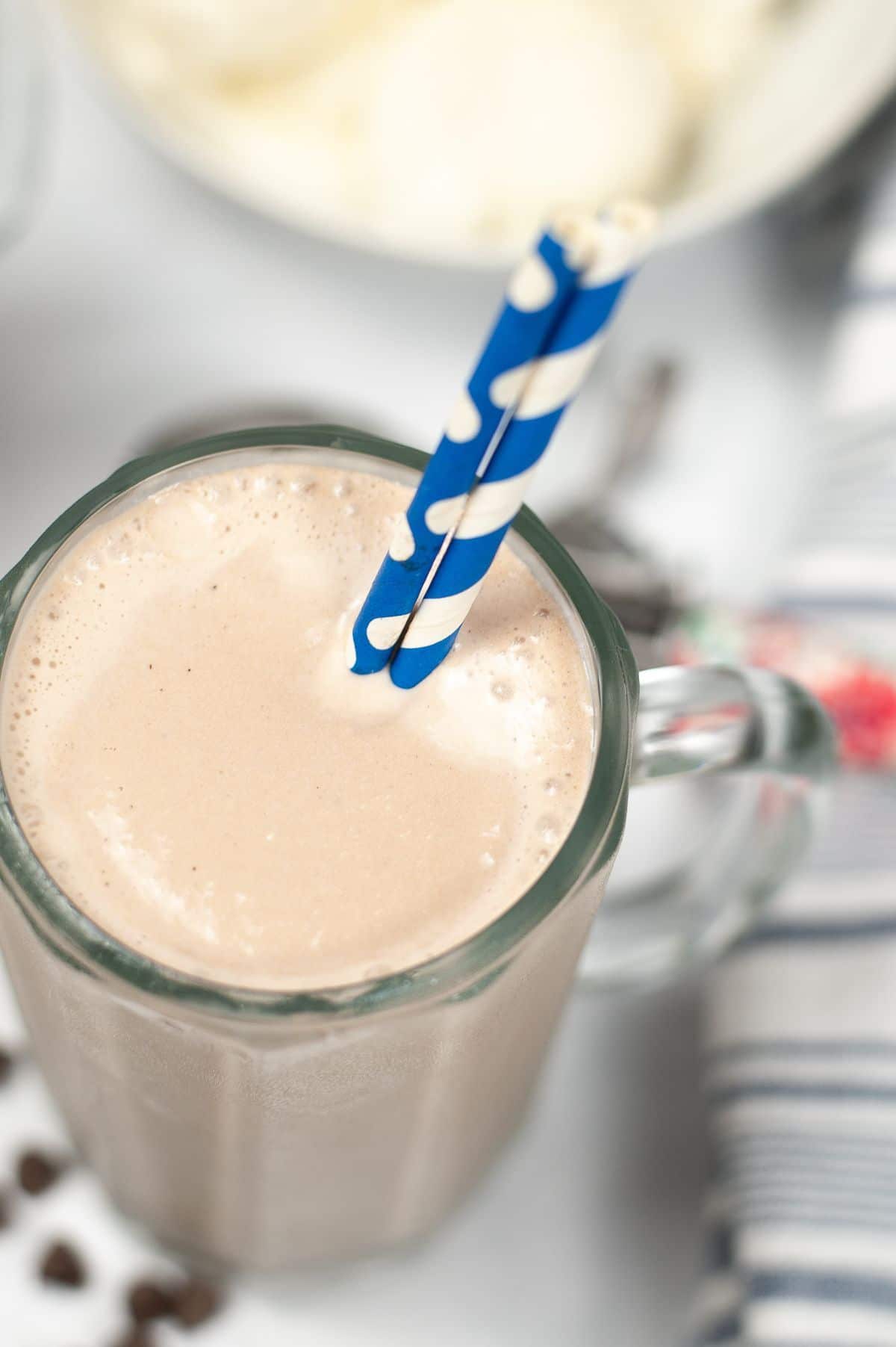 Close up shot of a serving of Wendy's Frosty Recipe in a glass with printed blue and white straws.