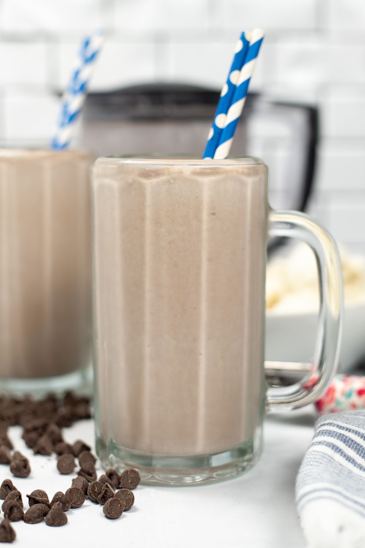 Vertical shot of a serving of Wendy's Frosty Recipe in a glass with printed straws in blue and white.