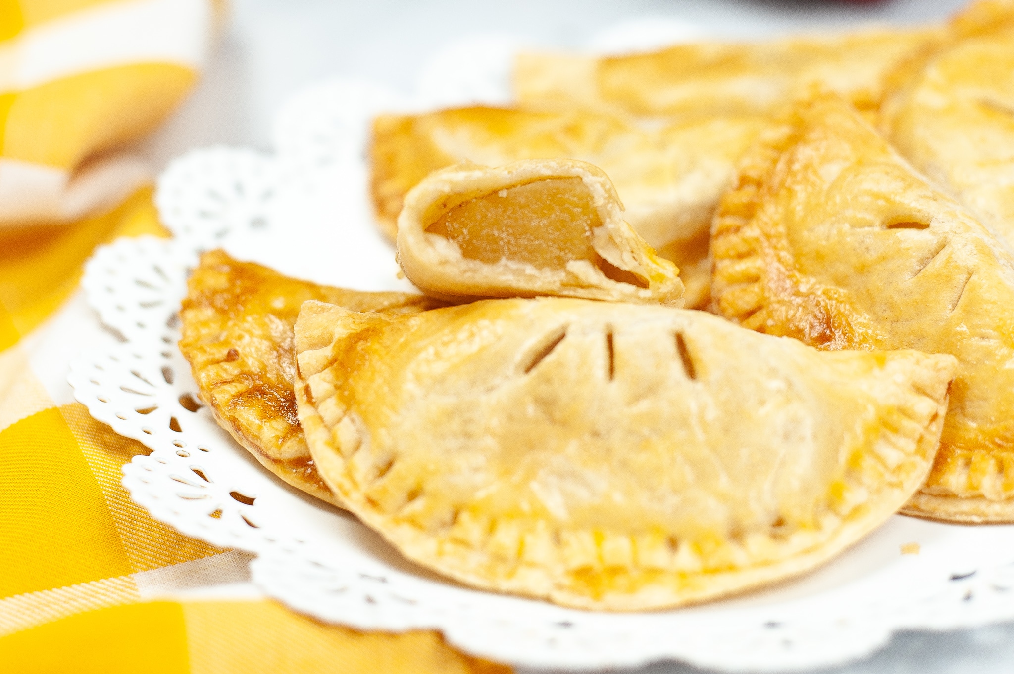 a closeup of Caramel Apple Hand Pies with one sliced in half so you can see the apple inside