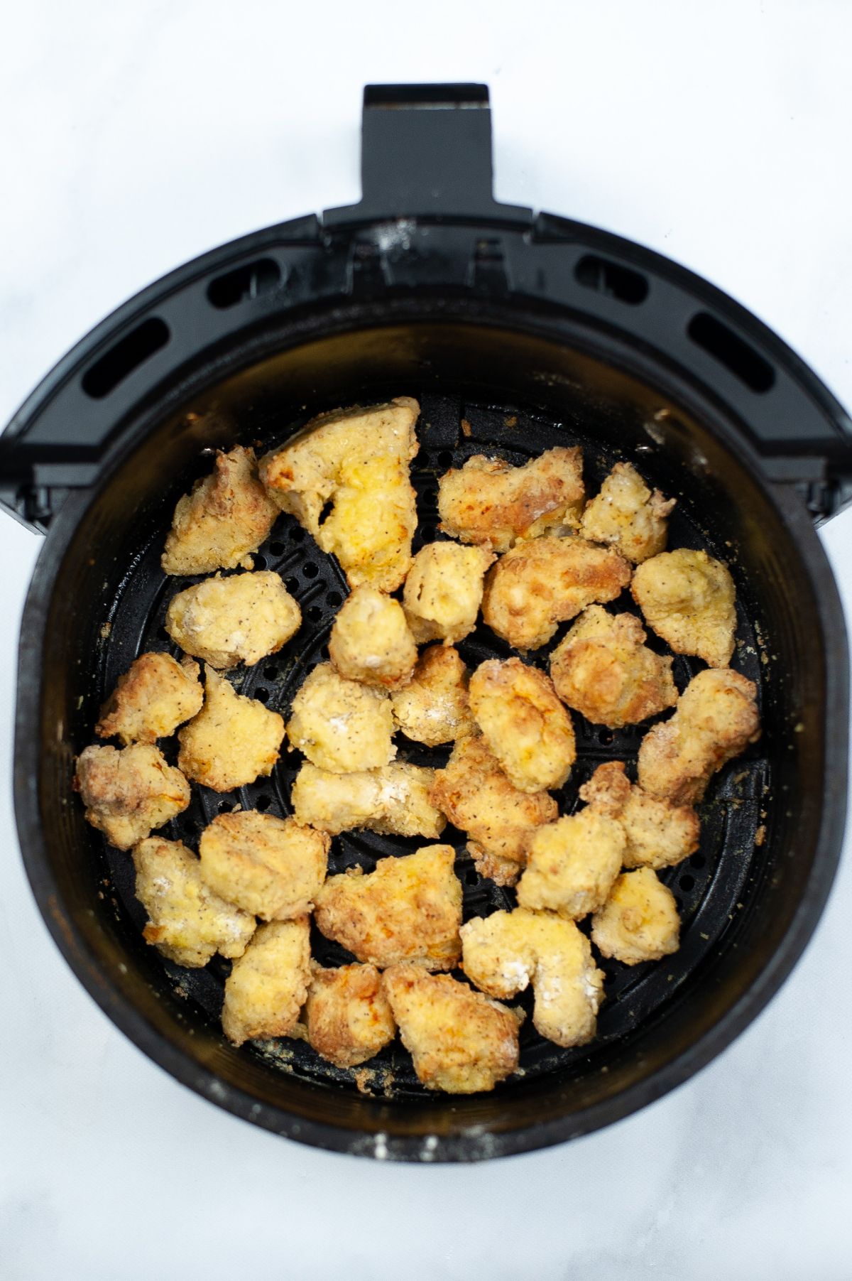 coated chicken cubes in an air fryer