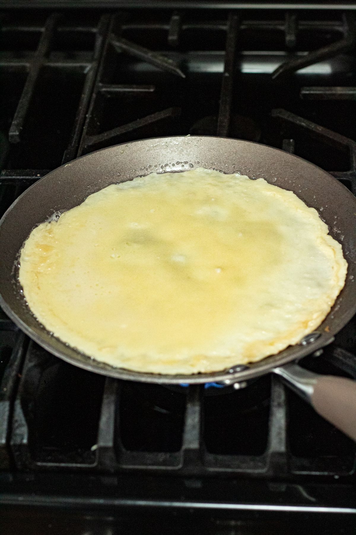 The batter being cooked on the skillet to make crepes.