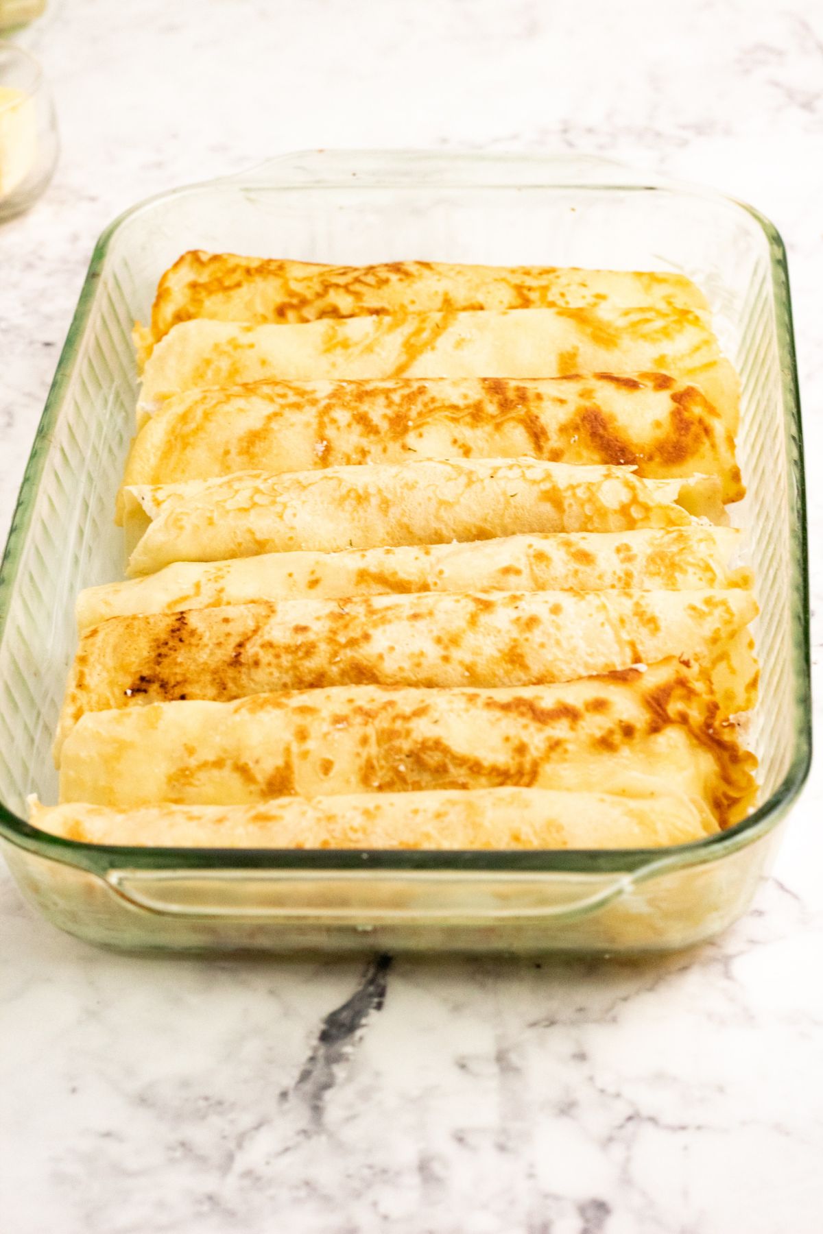 Assembled crepes on a baking dish.
