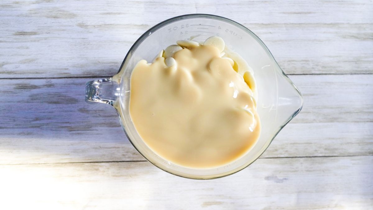 White chocolate melts and condensed milk in a microwave safe bowl.