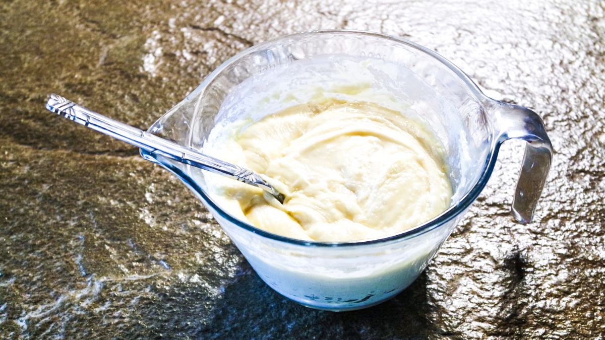 Melted White chocolate melts and condensed milk in a microwave safe bowl with a spoon in it.
