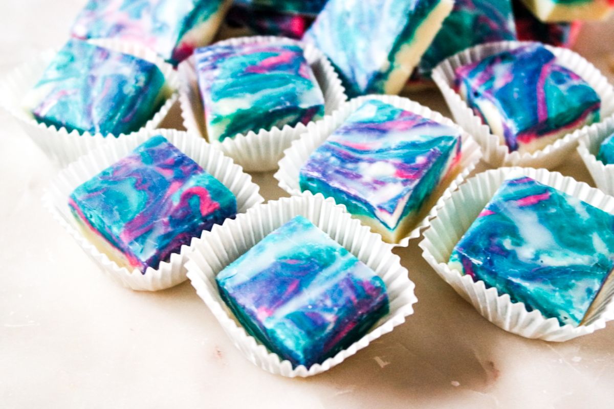 Horizontal shot of Cotton Candy Fudge in squares, with some of them in muffin cup wrappers.