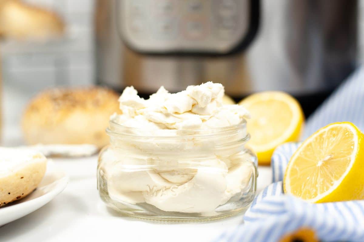 Instant Pot Cream Cheese in a mason jar with sliced lemons and an instant pot in the background