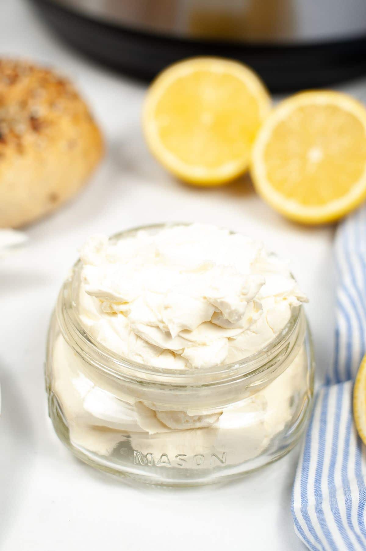 a closeup o f Instant Pot Cream Cheese in a mason jar with sliced lemons and an instant pot in the background