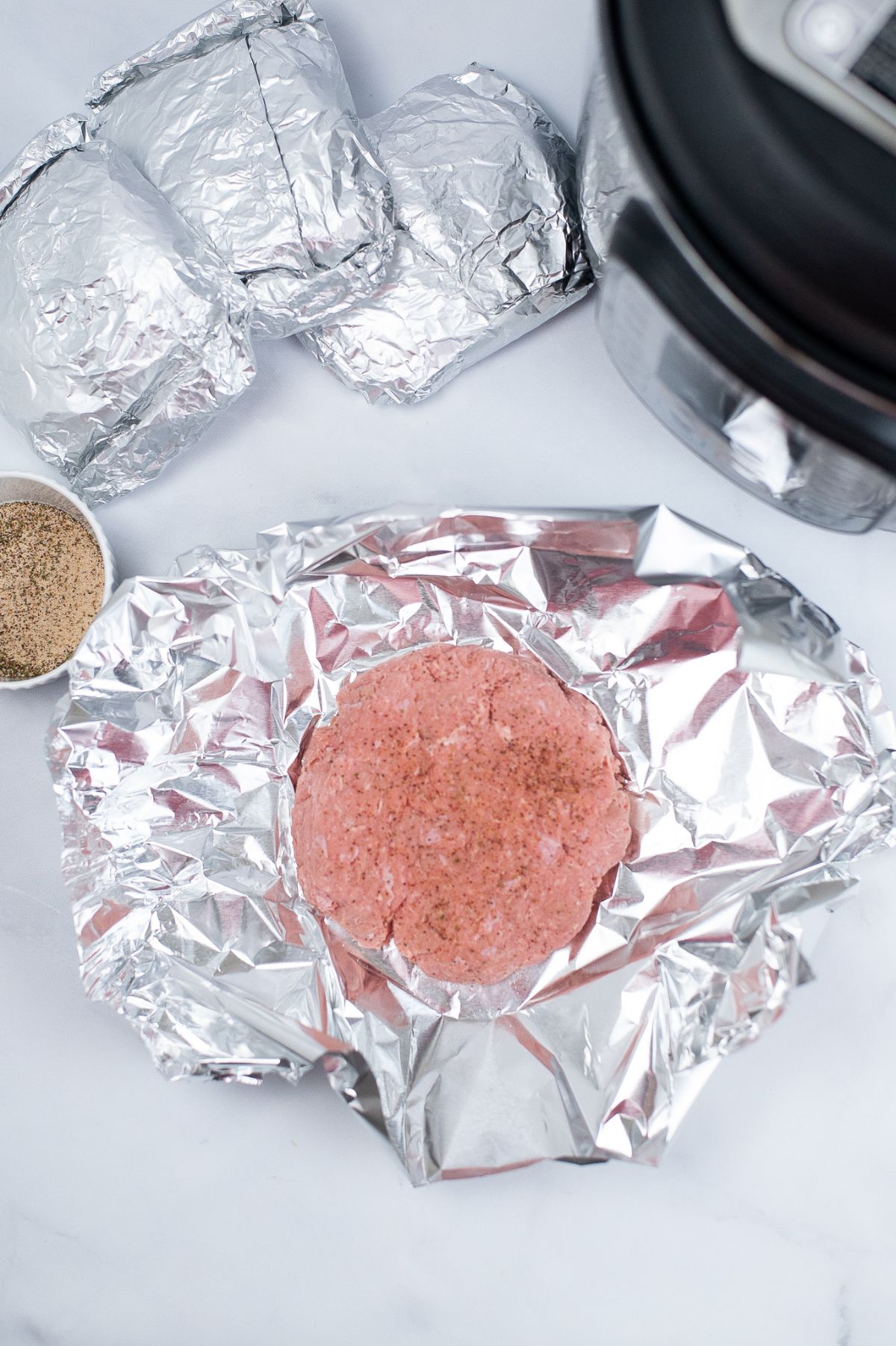 ground turkey meat shaped into patties and wrapped in a foil