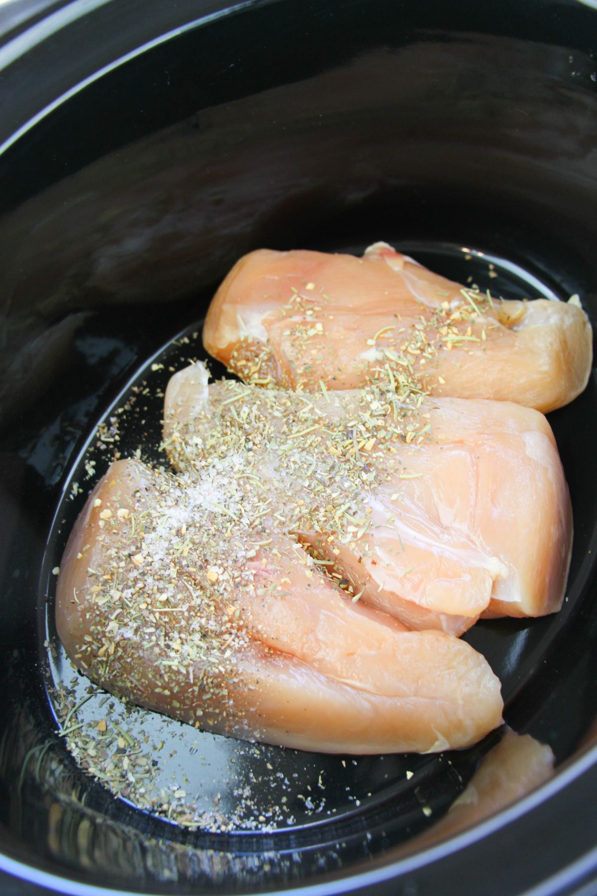 seasonings on 3 raw Chicken breasts in a crock pot