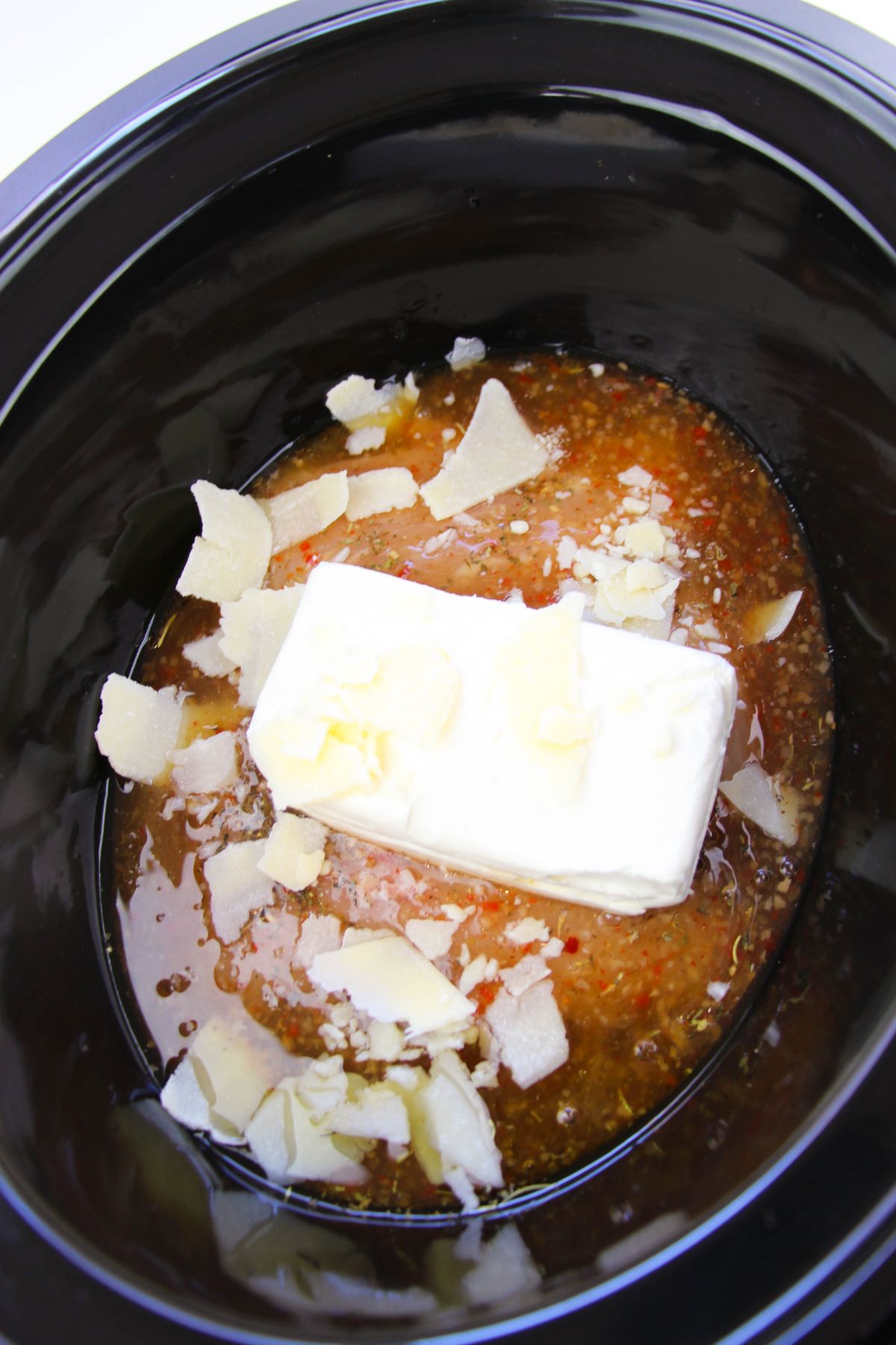 Italian dressing and cream cheese on top of the chicken breasts in the crock pot.