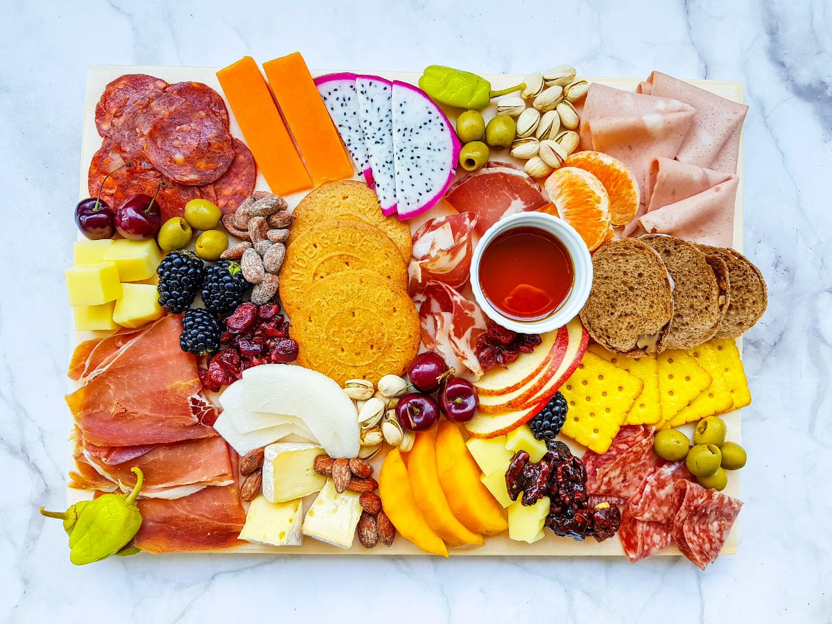 a charcuterie board with meats, cheese, crackers, nuts and fruit.