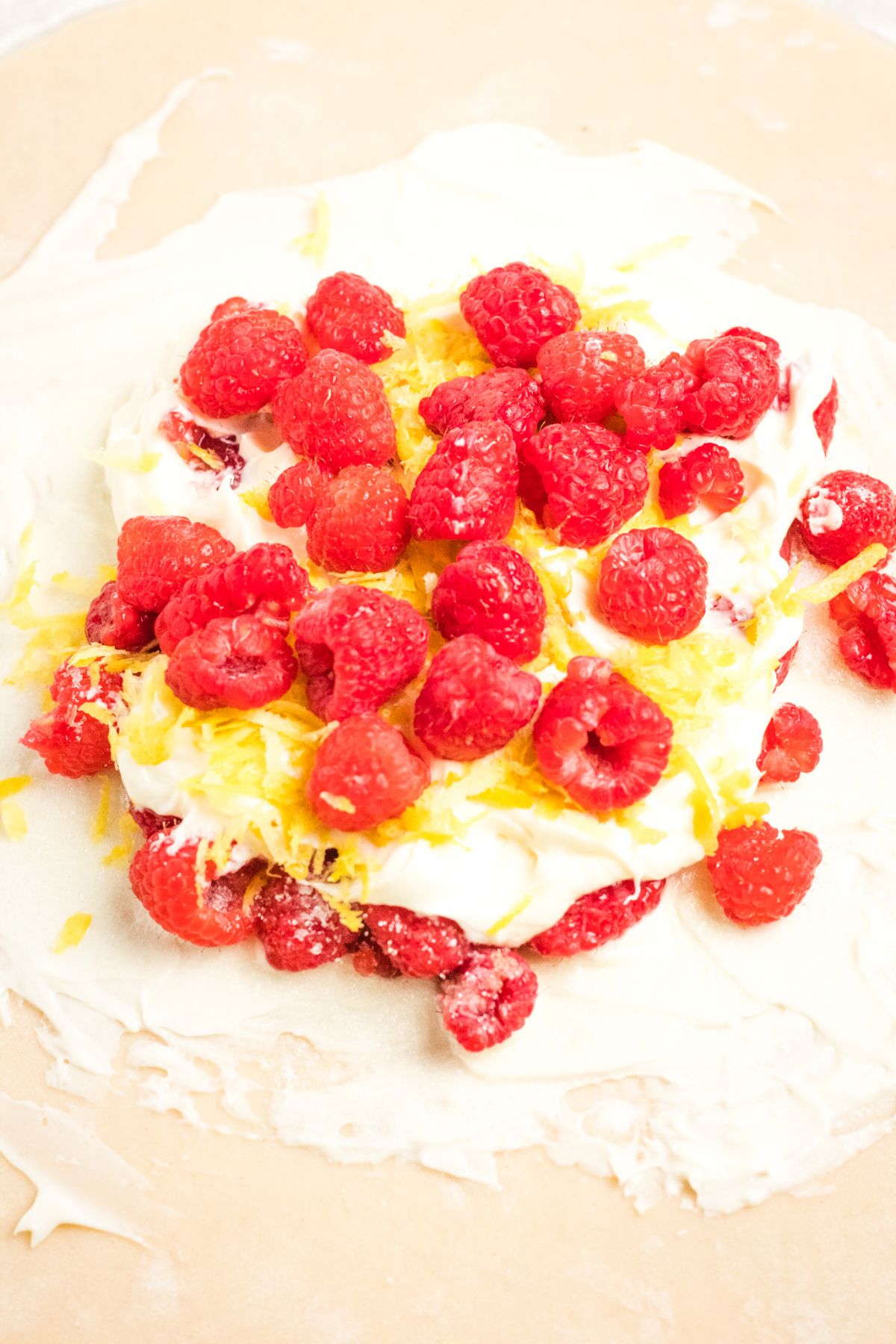 pie dough topped with a cream cheese mixture, raspberries and  lemon zest 