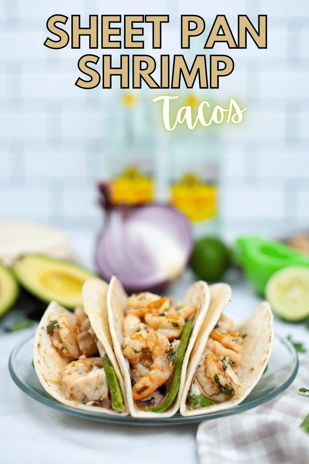 Sheet Pan Shrimp Tacos on a glass plate with an avocado, onion and limes blurred in the background with title text reading Sheet Pan Shrimp Tacos