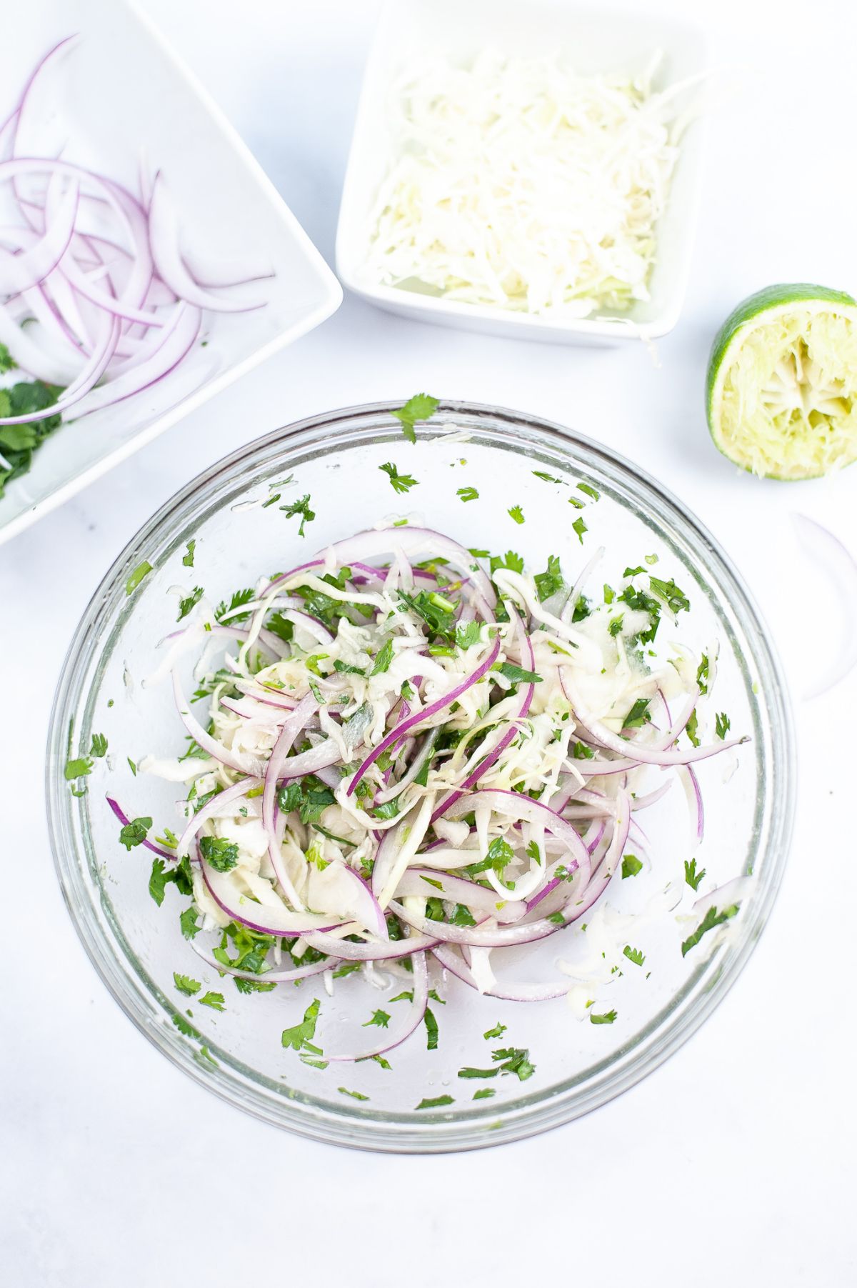 Shredded cabbage, onion and cilantro in a glass bowl