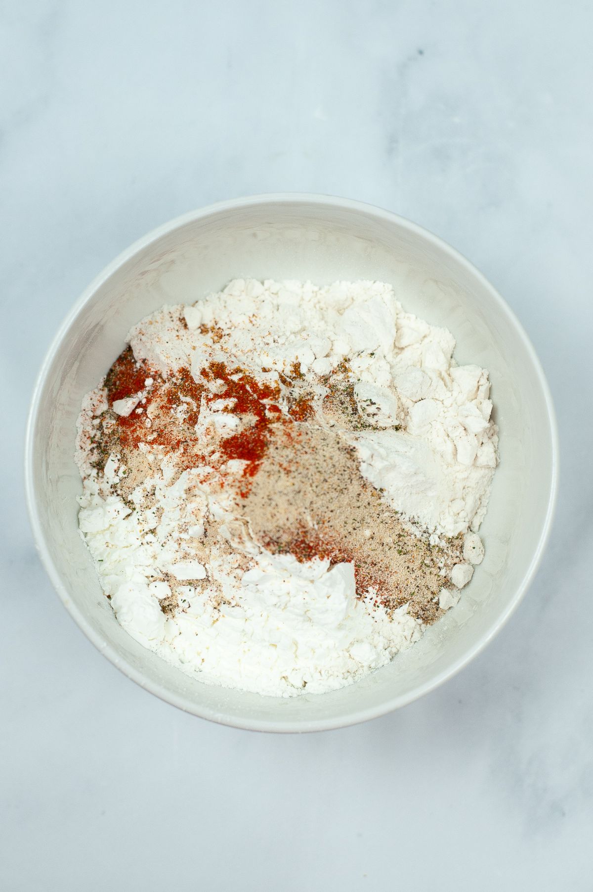 spices, flour and cornstarch in a white bowl. 
