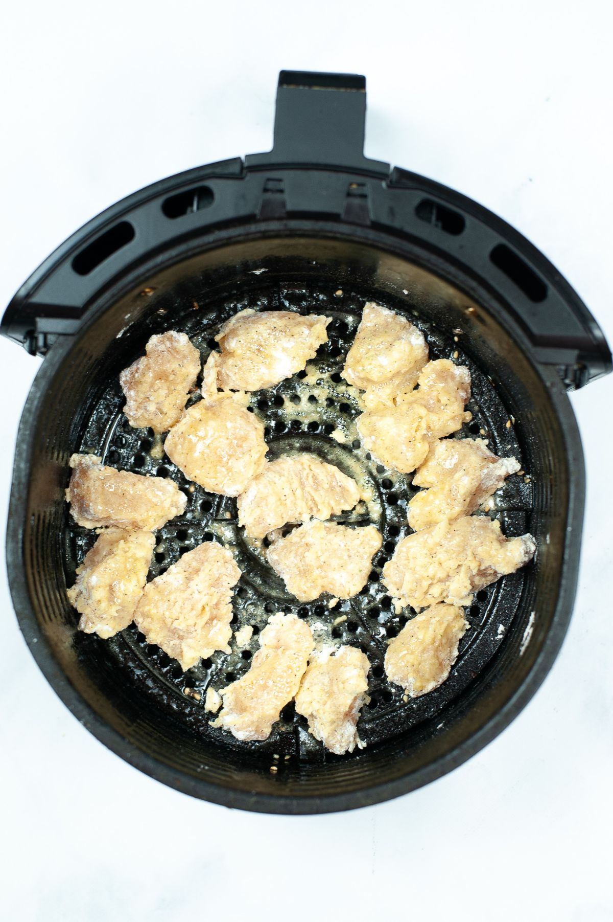 coated chicken pieces being cooked in an air fryer