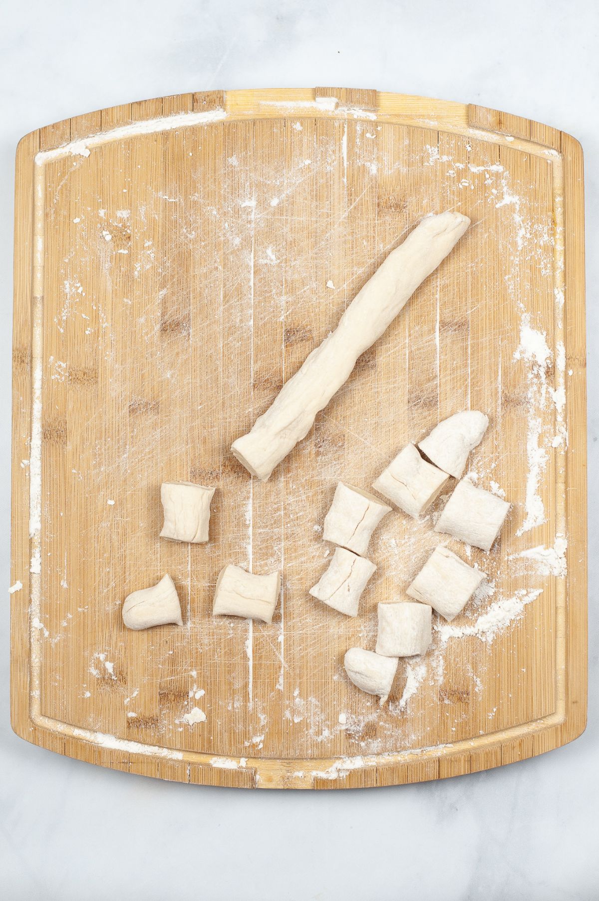 dough rolled into ropes and some cut pieces on a wooden cutting board