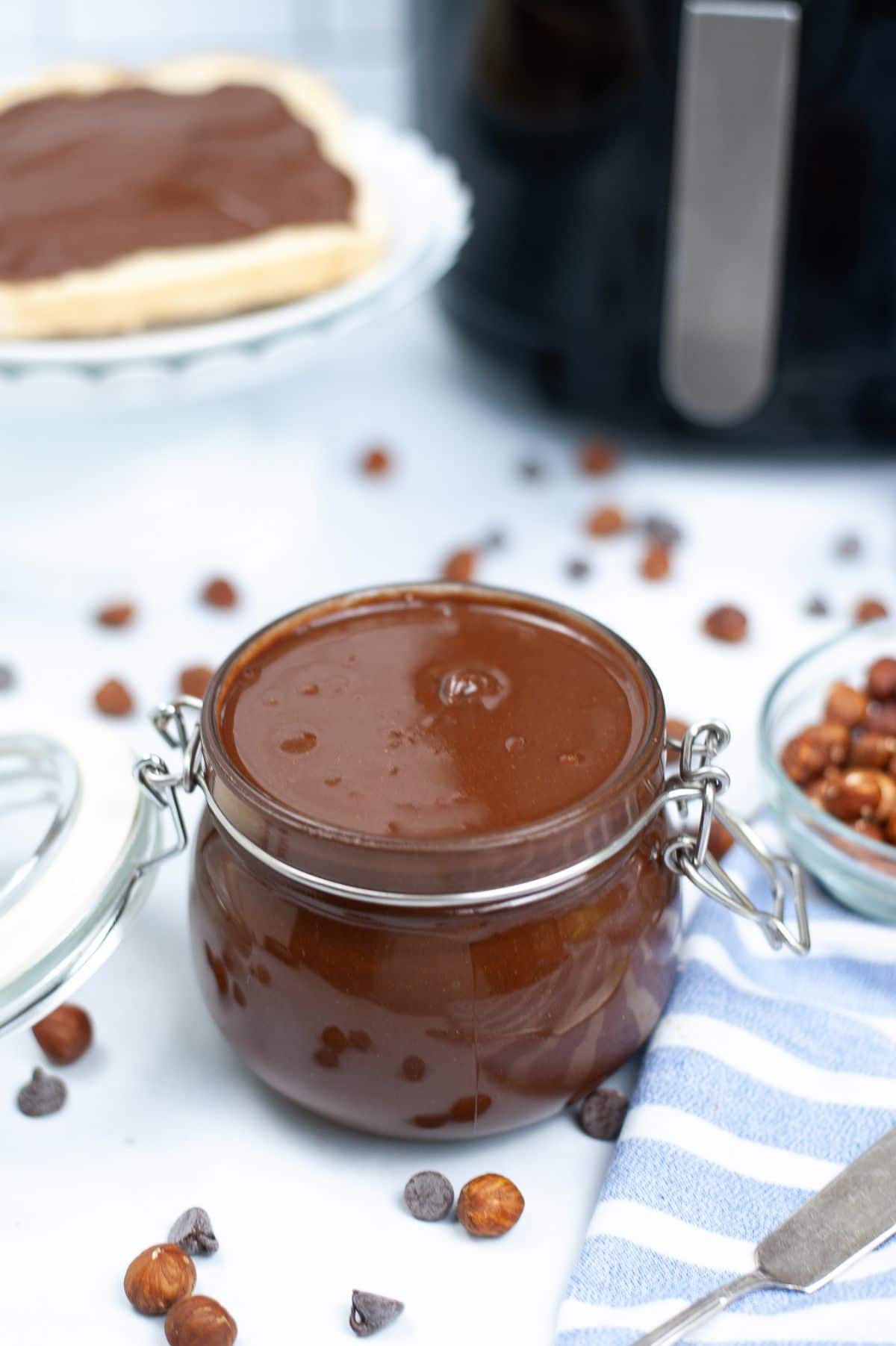 Homemade Nutella in a jar with an air fryer blurred in the background