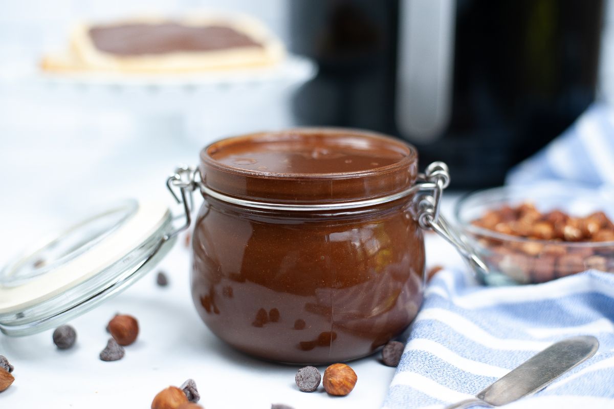 Homemade Nutella in a jar with an air fryer blurred in the background