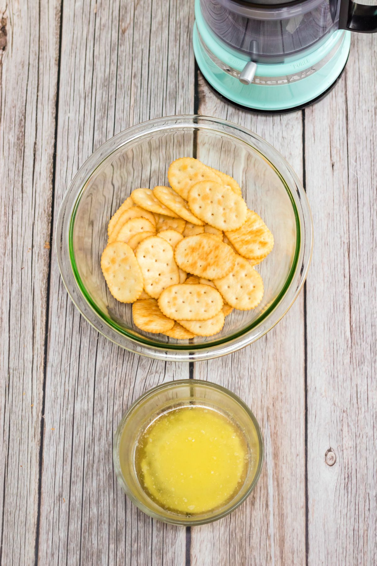 Crackers and lemon juice in clear glass bowls on a wood table