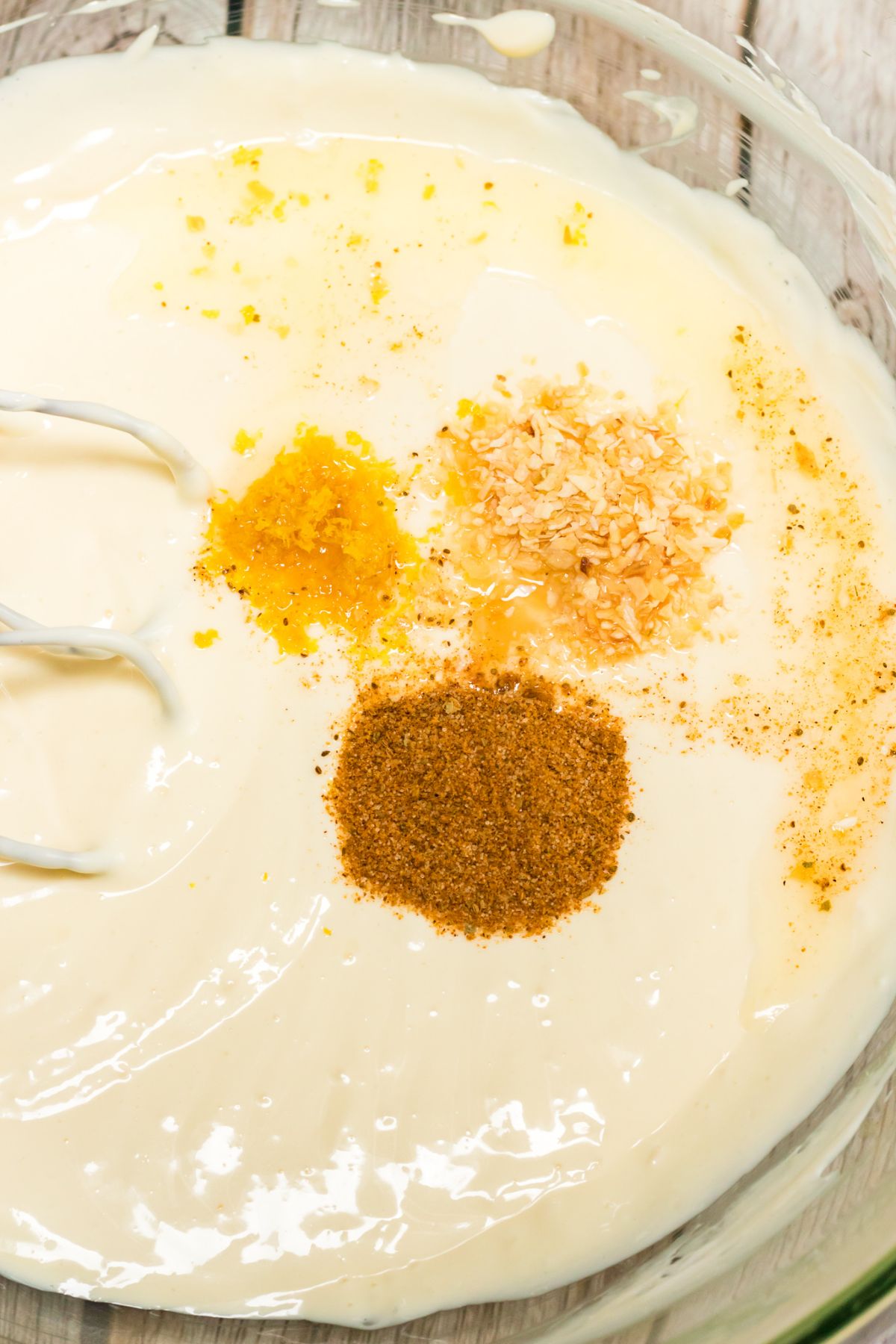 cream cheese, buttermilk, eggs, lemon juice, lemon zest and seasonings being mixed in a clear bowl