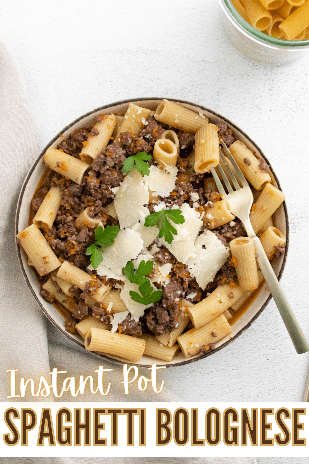 Instant Pot Spaghetti Bolognese on a white plate topped with parmesan cheese and parsley with a fork on the side with title text reading Instant Pot Spaghetti Bolognese