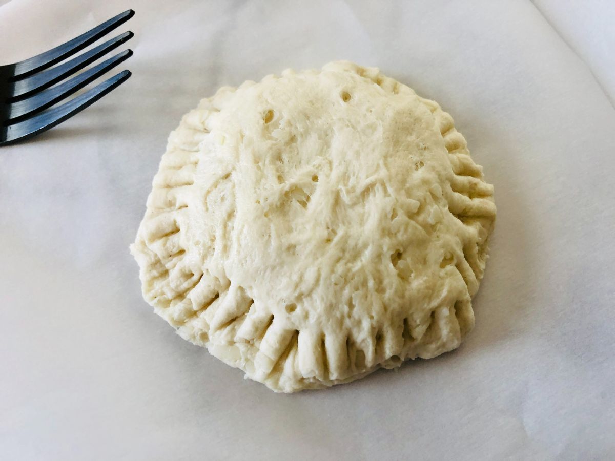 an uncooked biscuit hot pocket sealed with a fork