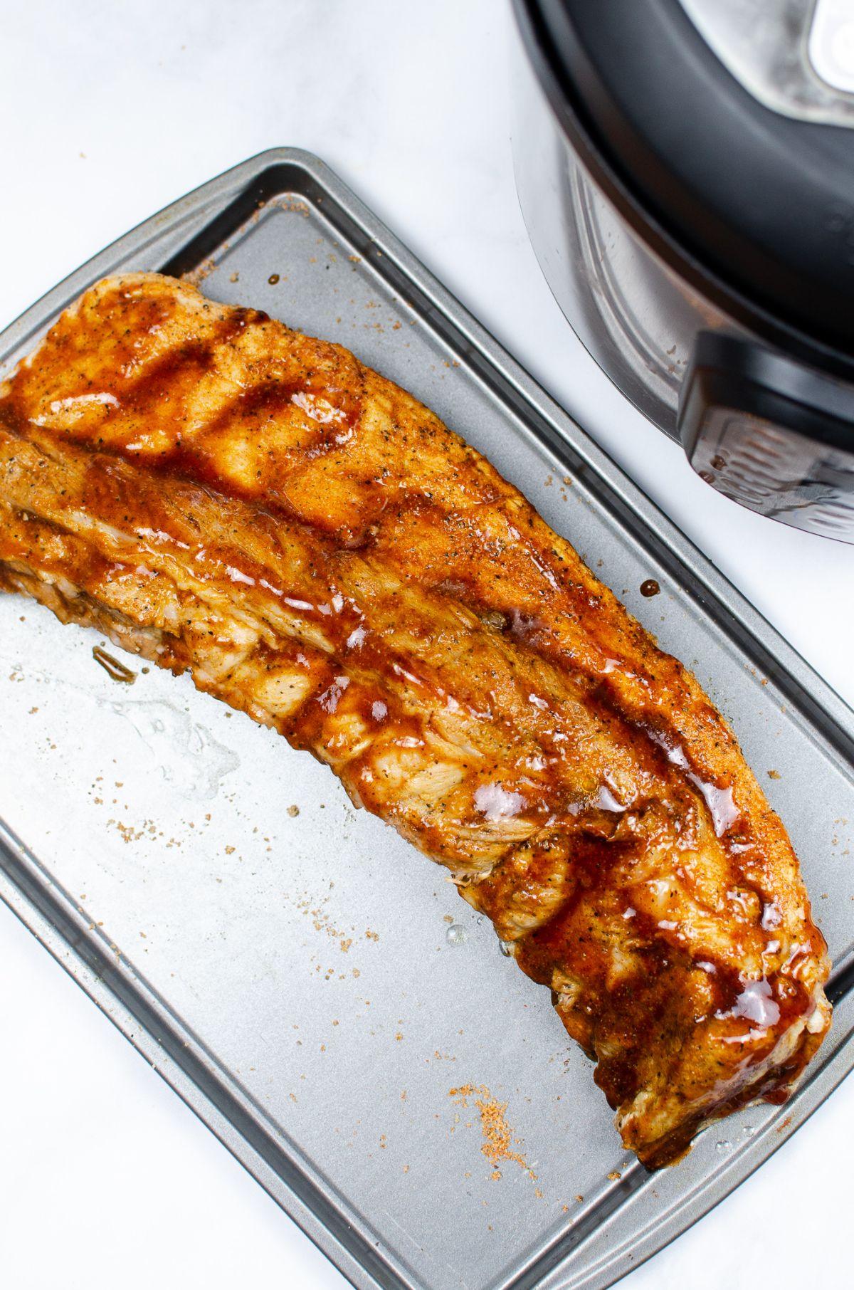ribs topped with barbecue sauce on a baking pan  