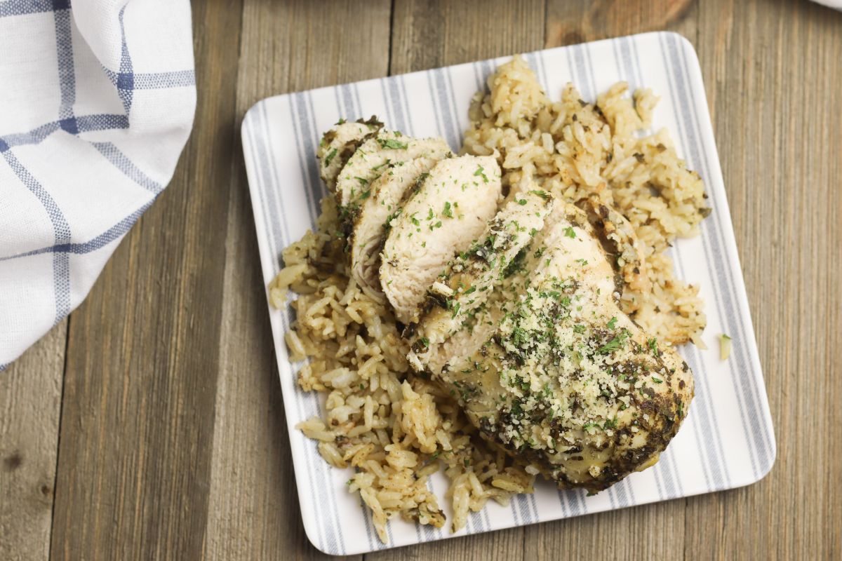 overhead view of Instant Pot Chicken Breasts and Rice on a plate garnished with parmesan cheese and parsley with a blue and white cloth  in the background