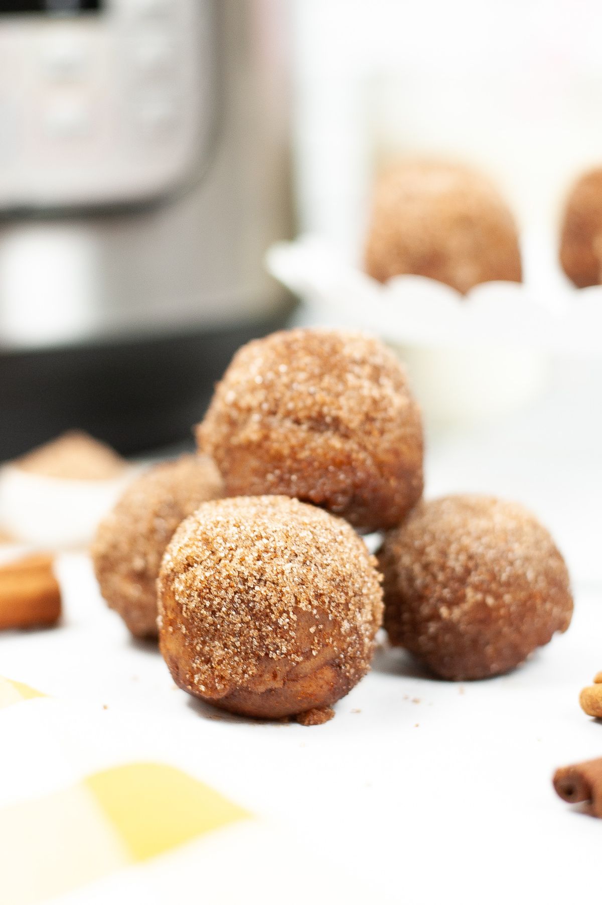 Instant Pot Churro Bites coated in cinnamon and sugar with an instant pot and more churro bites blurred in the background