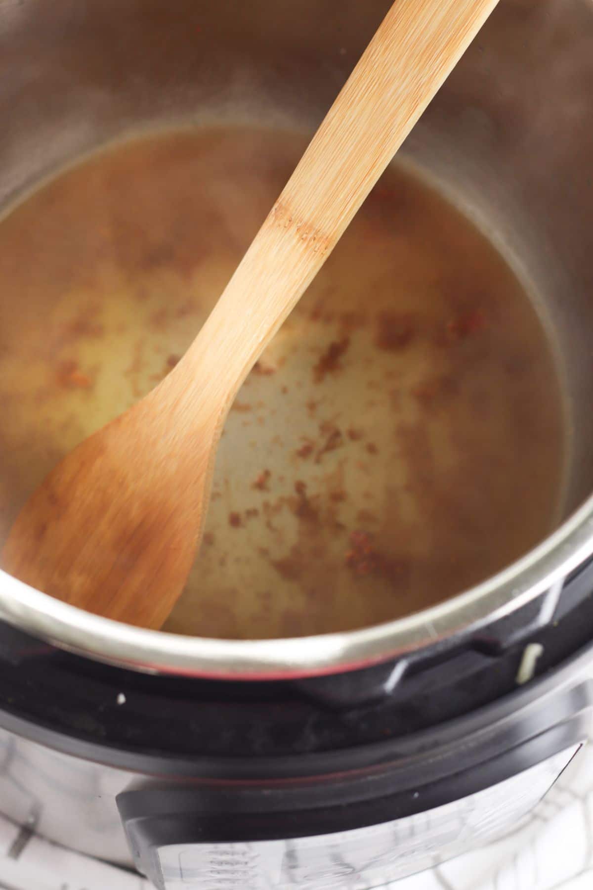 Deglaze Instant Pot with a wooden spoon