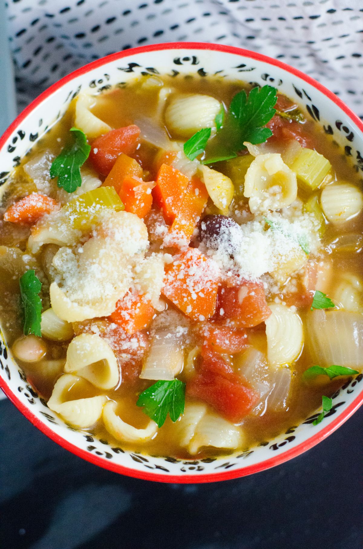 a closeup of Instant Pot Pasta Fagioli in a bowl garnished with parsley leaves and parmesan cheese