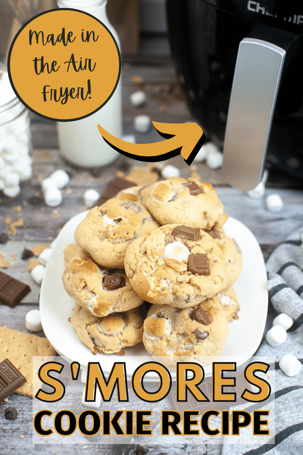 a stack of cookies made from an Air Fryer Smores Cookie Recipe on a plate surrounded by graham crackers, chocolate bars, chocolate chips and marshmallows with title text reading Made in the Air Fryer S'mores Cookie Recipe