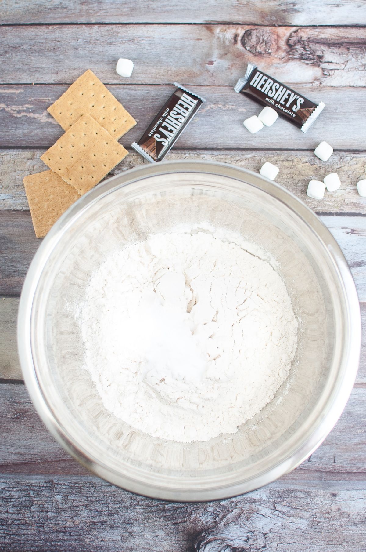 salt, baking powder, cornstarch, and flour in a separate bowl next to graham crackers, Hershey;s chocolate bars, and marshmallows