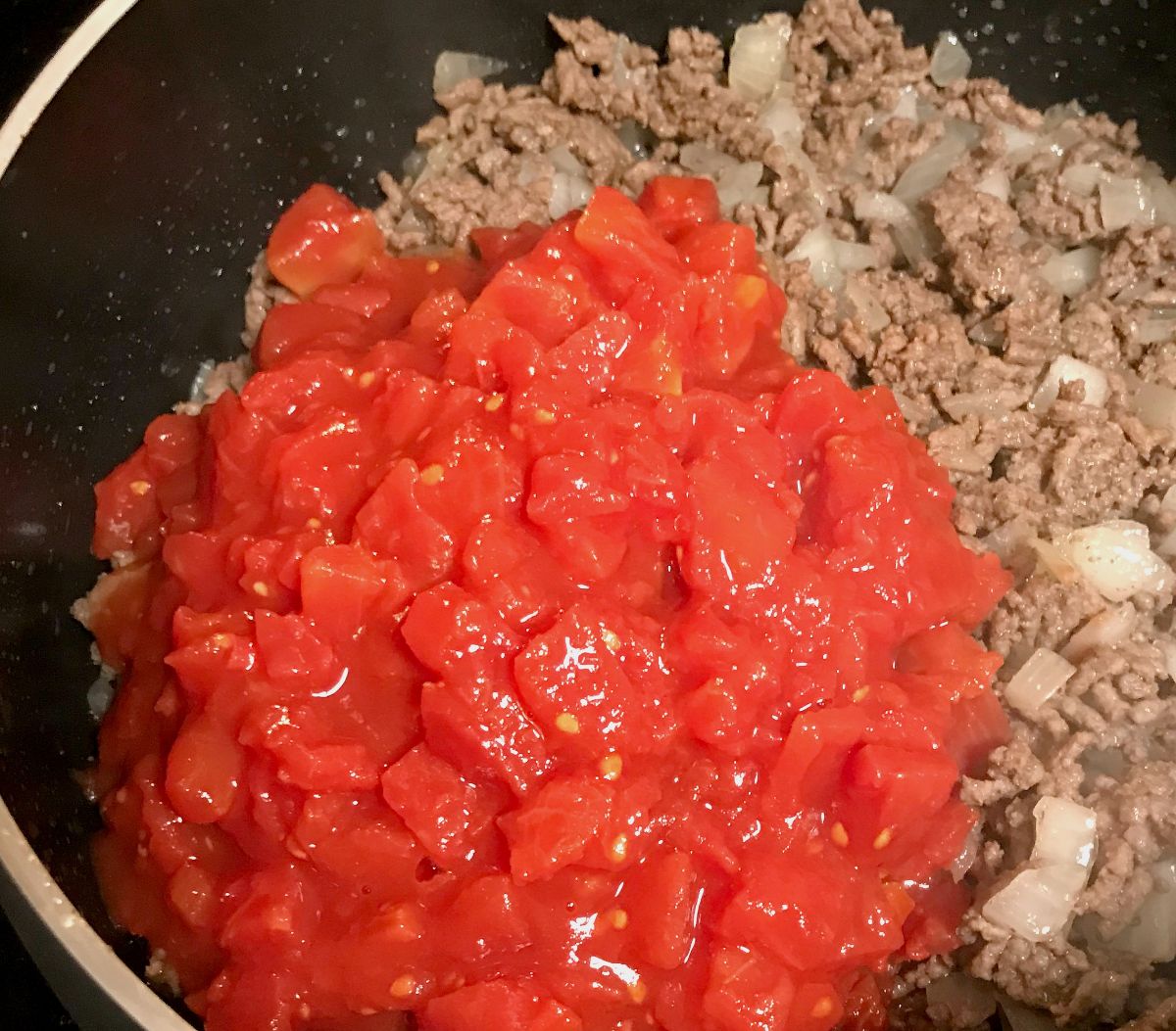 Ground beef, onions and tomatoes in a large skillet