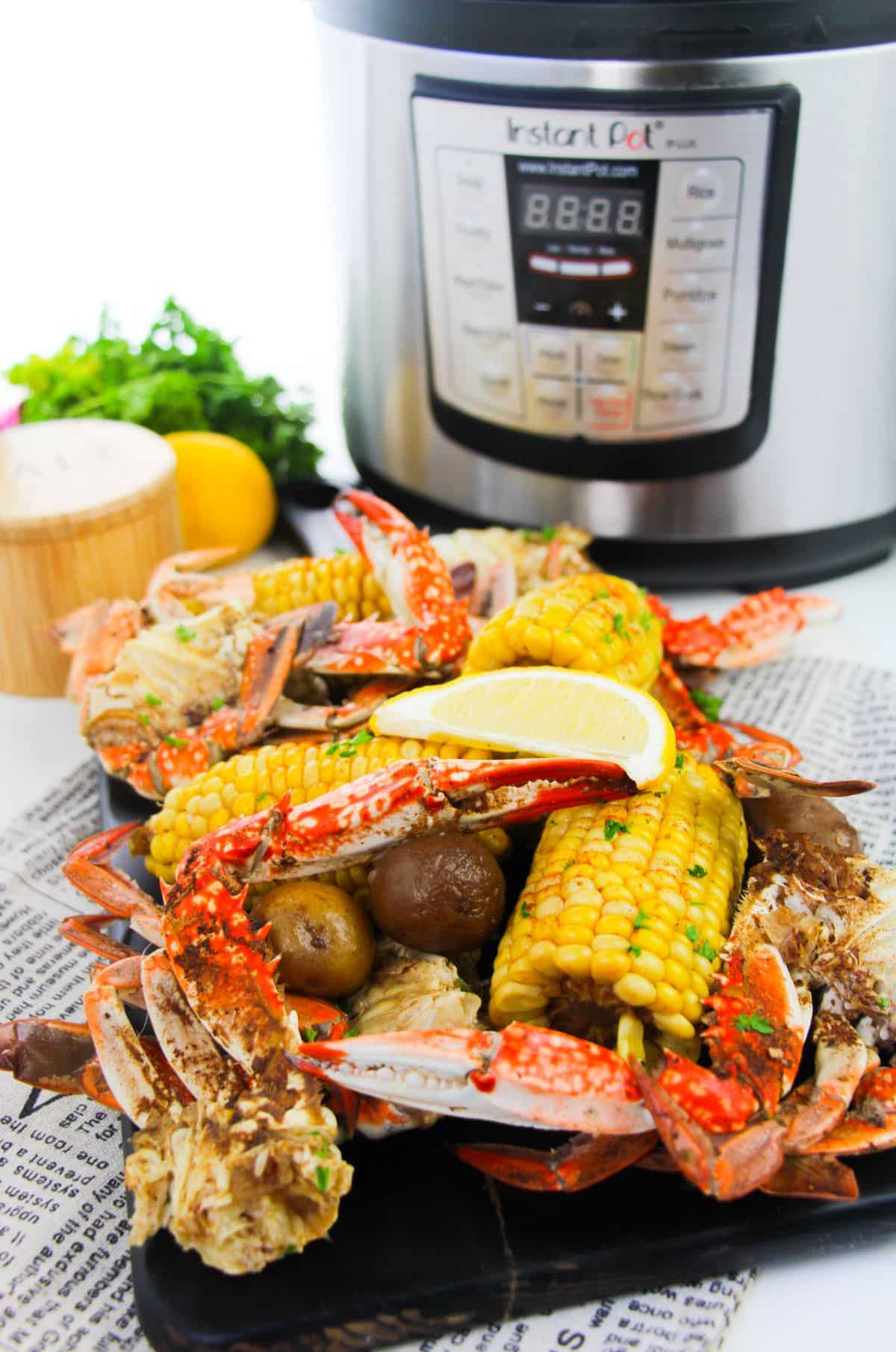 Instant Pot Crab Boil on a platter  garnished with chopped parsley with an instant pot in the background