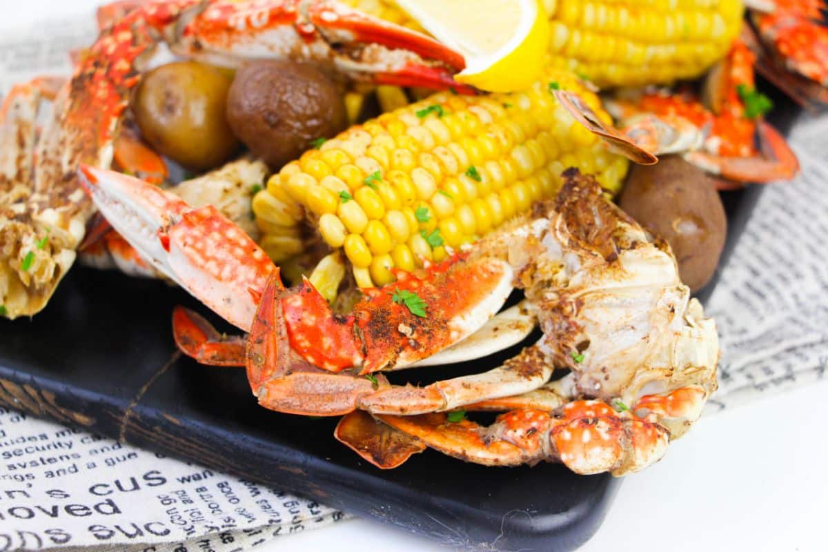 Instant Pot Crab Boil on a platter garnished with chopped parsley with an instant pot in the background
