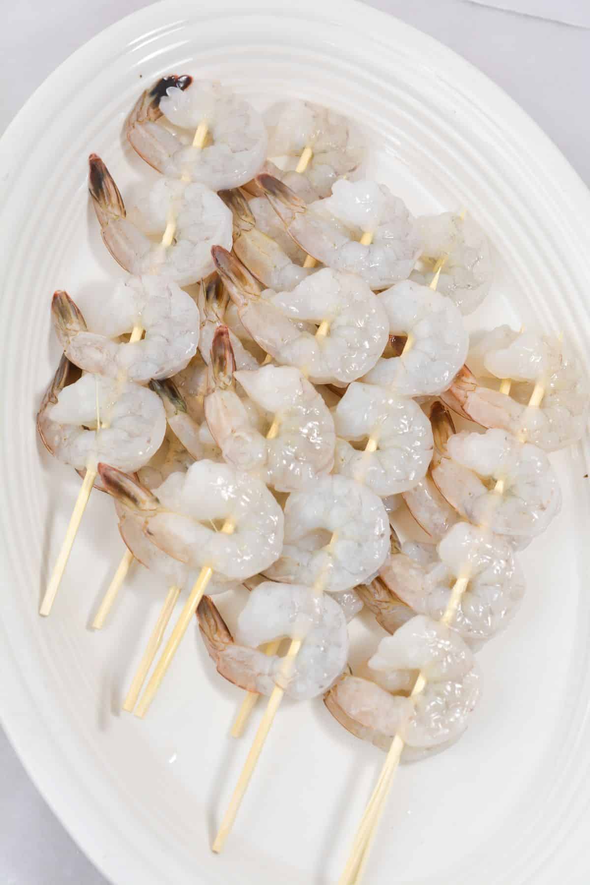 Shrimp on wooden skewers on a white platter