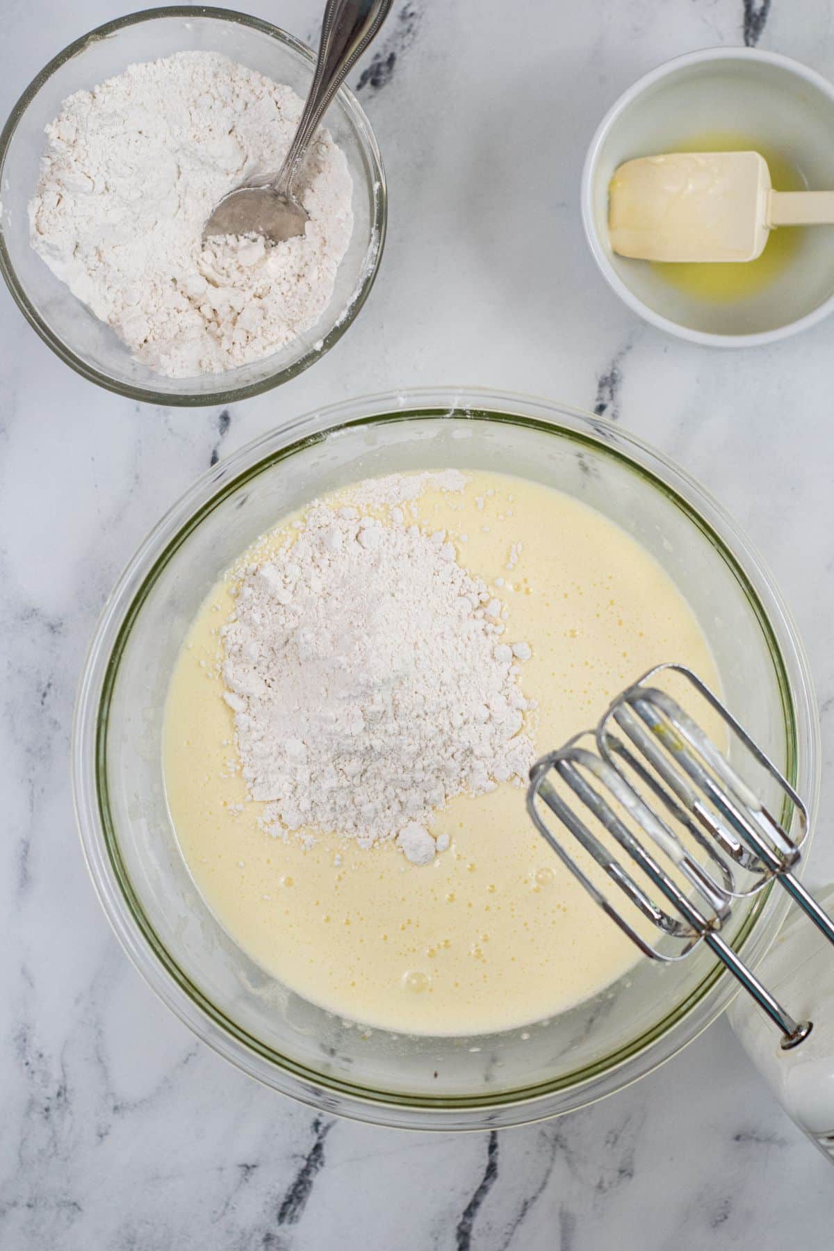 Flour and wet ingredients with hand mixer in a glass bowl