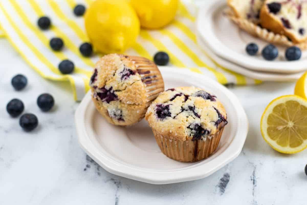 Lemon Blueberry Muffins With Sour Cream on a plate with blueberries and lemons in the background