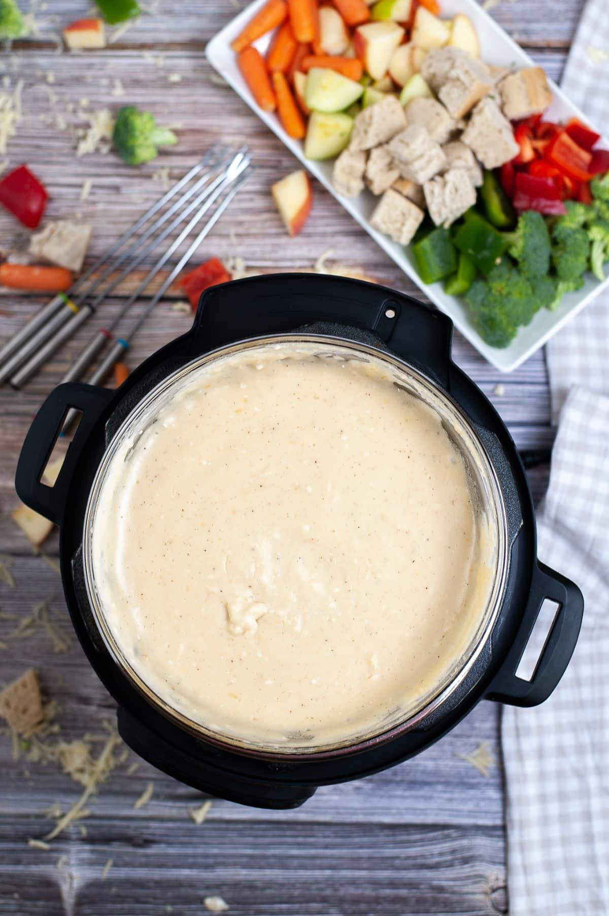 Swiss cheese fondue made in the Instant Pot, with vegetables on the side on a white platter