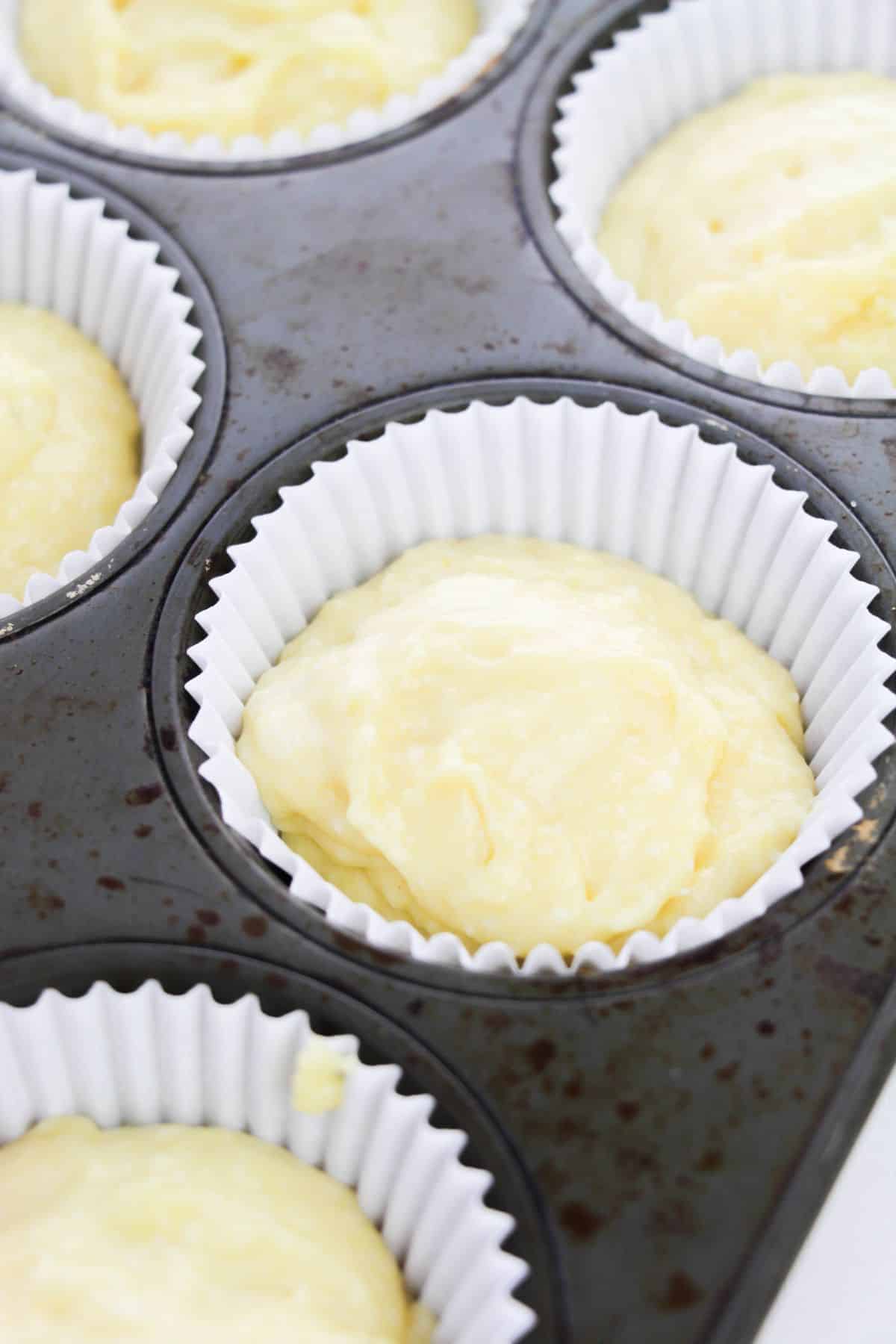 closeup of cupcake liners filled with muffin batter in a muffin pan