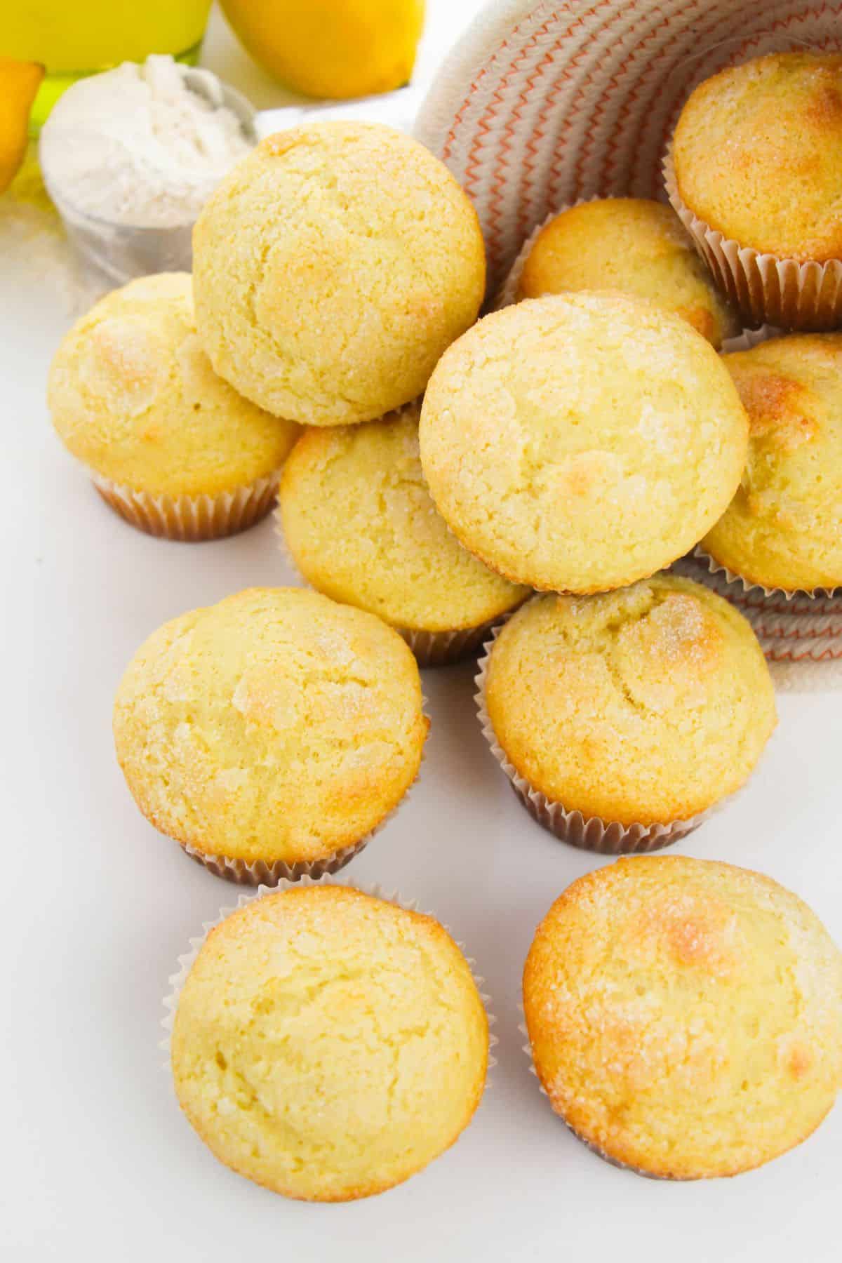 Ricotta Lemon Muffins in a basket and on a table with lemon and flour on the side