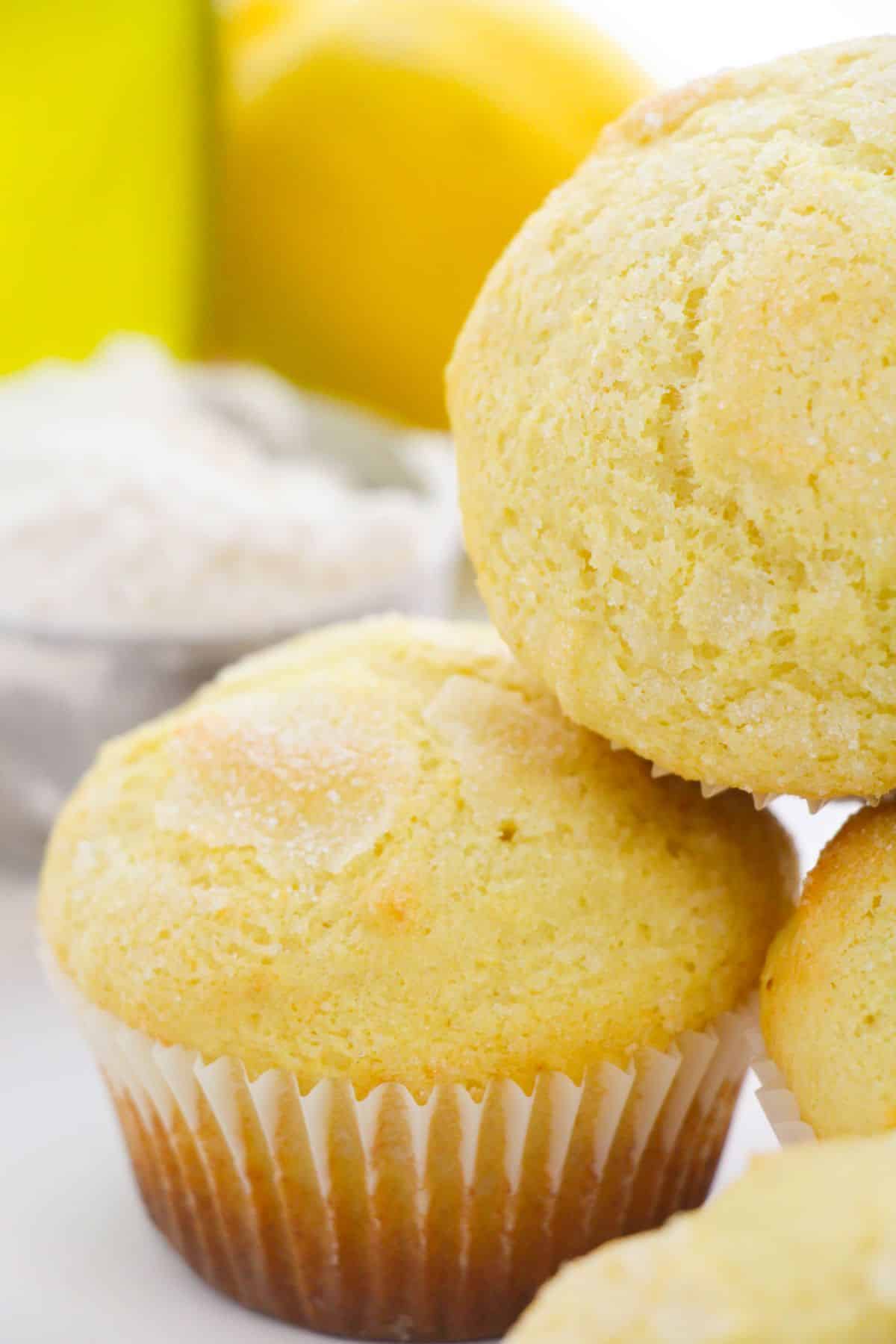 a closeup of Ricotta Lemon Muffins with lemon and flour blurred in the background