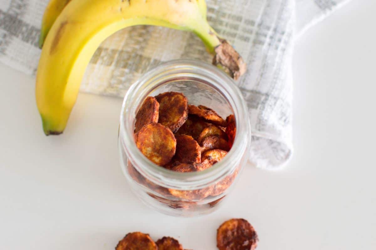 overhead view of Air Fryer Banana Chips in a jar with a banana on the side
