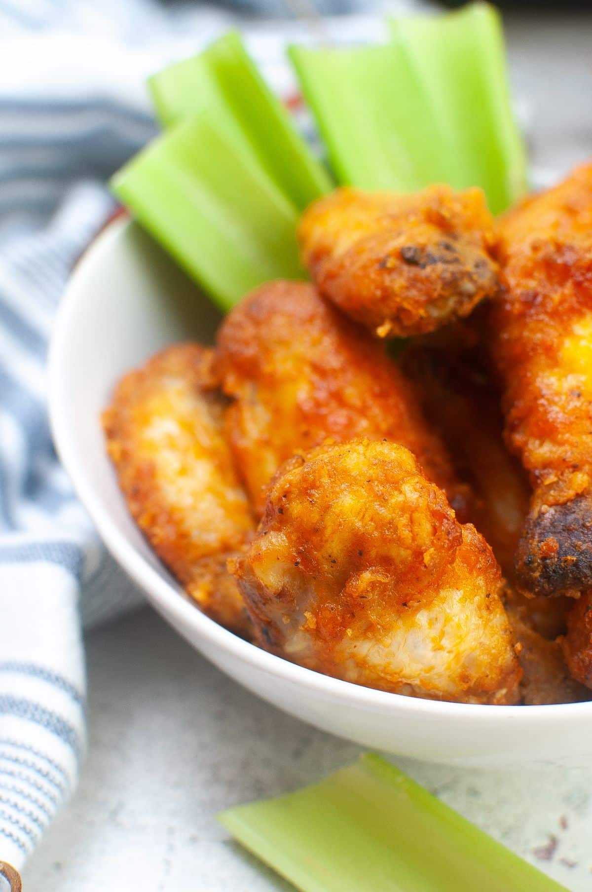 closeup of Air Fryer Buffalo Wings in a large bowl next to celery stalks