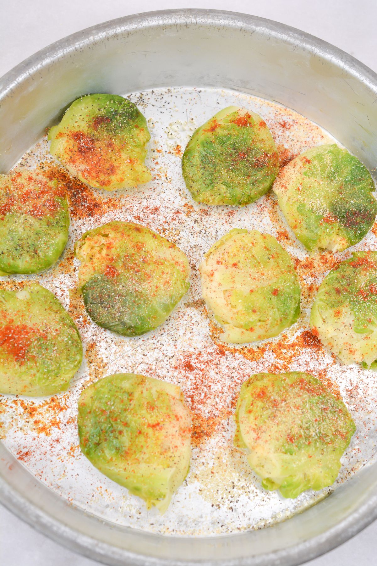 Brussels sprouts in a pan seasoned with garlic powder, onion powder, paprika, salt and pepper
